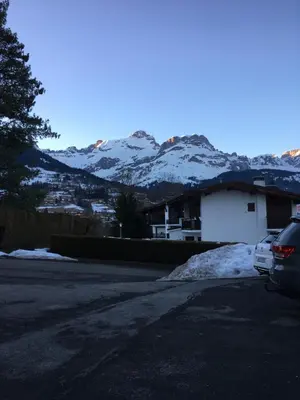 a car parked in front of a house with snow covered mountains at Sallanches 3101 Route de Nant Cruy immeuble le Grand R in Sallanches