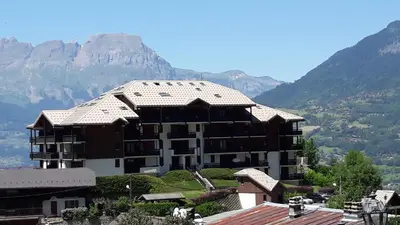 a large apartment building with mountains in the background at Appartement Saint Gervais les Bains in Saint-Gervais-les-Bains