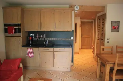 a kitchen with wooden cabinets and a red couch and a table at At Home in Les Carroz d'Araches