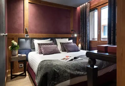 a bedroom with a large bed with a wooden headboard at MGM Hôtels & Résidences - Hôtel Les Suites d'Alexane in Samoëns