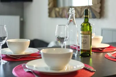 a table with a bottle of wine and two glasses at Apartment Aiglons - Central Chamonix Mountain Haven in Chamonix-Mont-Blanc