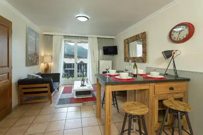 a living room with a table and two stools at Apartment Aiglons - Central Chamonix Mountain Haven in Chamonix-Mont-Blanc