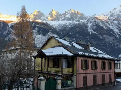 a house with snow on the roof in front of mountains at Apartment Le Chalet Suisse-3 by Interhome in Chamonix-Mont-Blanc