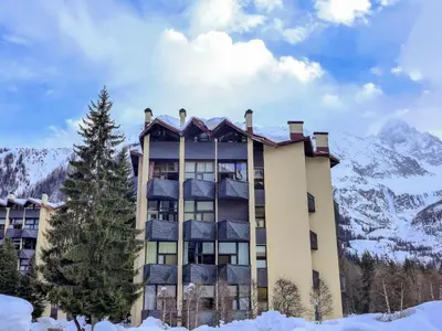 a building with snow covered mountains in the background at Apartment Grand Roc-4 by Interhome in Chamonix-Mont-Blanc