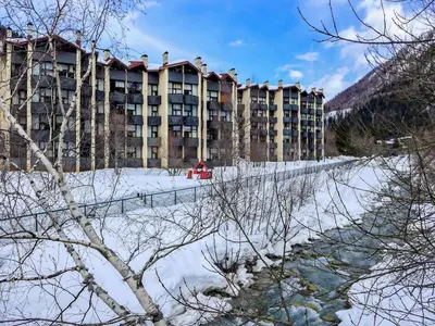 a large building in the snow next to a river at Apartment Grand Roc-4 by Interhome in Chamonix-Mont-Blanc