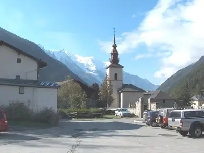 a church with a steeple and cars parked in a parking lot at Apartment Grand Roc-4 by Interhome in Chamonix-Mont-Blanc