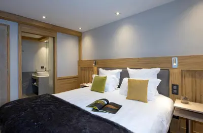a bedroom with a large bed with two books on it at MGM Hôtels & Résidences - Résidence Chalets Elena in Les Houches