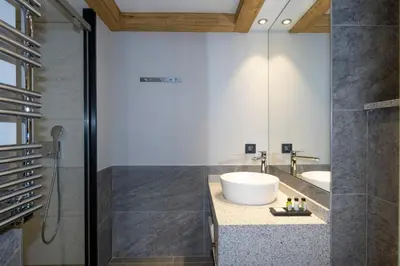 a bathroom with a white sink and a shower at MGM Hôtels & Résidences - Résidence Chalets Elena in Les Houches