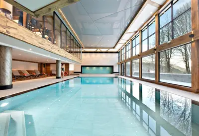 an indoor swimming pool with a large room with windows at MGM Hôtels & Résidences - Résidence Chalets Elena in Les Houches