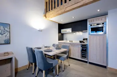 a kitchen with a dining room table and chairs at MGM Hôtels & Résidences - Résidence Chalets Elena in Les Houches