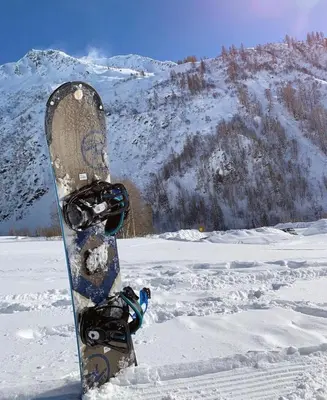 a snowboard sitting in the snow with a mountain in the background at Giffre in Samoëns