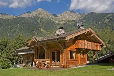 a log cabin with mountains in the background at Chalet Rimaye - Chamonix in Chamonix-Mont-Blanc