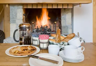 a table with plates of food in front of a fireplace at Chalet Rimaye - Chamonix in Chamonix-Mont-Blanc
