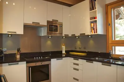 a kitchen with white cabinets and black counter tops at Chalet Rimaye - Chamonix in Chamonix-Mont-Blanc