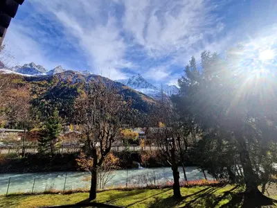 a view of a river with trees and mountains at Studio lumineux avec vue sur le massif du Mont-Blanc in Chamonix-Mont-Blanc
