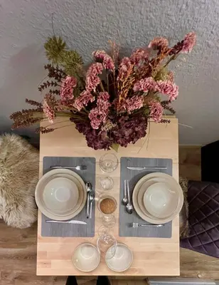 a table with two plates and a vase of flowers at Rocky Studio Chamonix Sud in Chamonix-Mont-Blanc