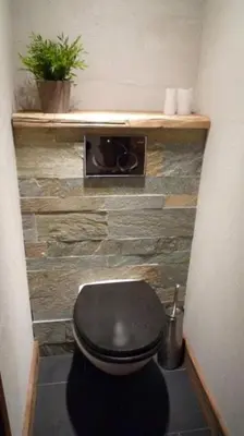 a bathroom with a black toilet in a room at Appartement du Petit Bois in Megève