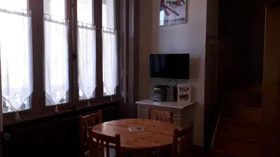 a room with a table and a television and a table and chairs at joli T3 proche centre et télécabines in Saint-Gervais-les-Bains