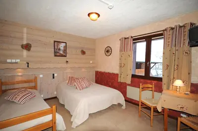 a bedroom with two beds and a tv and a window at La Boule de Neige in Samoëns