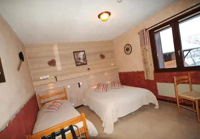 a small room with two beds and a window at La Boule de Neige in Samoëns