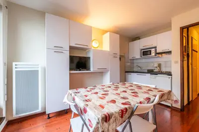 a kitchen with white cabinets and a table with chairs at Le Sapi 1E Balcon panoramique Aiguilles Rouges avec parking gratuit in Chamonix-Mont-Blanc