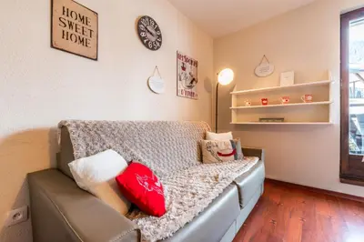 a room with a couch with pillows and a clock at Le Sapi 1E Balcon panoramique Aiguilles Rouges avec parking gratuit in Chamonix-Mont-Blanc