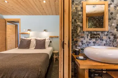 a bedroom with a bed and a bathroom with a sink at Les Rives d'Argentière in Chamonix-Mont-Blanc