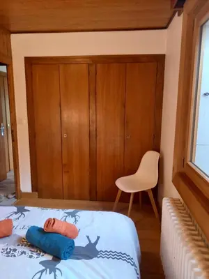 a small bedroom with a bed and a chair at Appartement avec Terrasse in Chamonix-Mont-Blanc