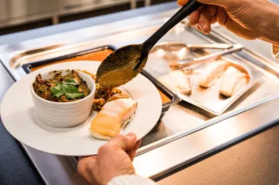 a person holding a plate of food with a spoon at Village Vacances le Bérouze in Samoëns