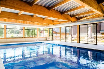 a large swimming pool in a large room with windows at Village Vacances le Bérouze in Samoëns