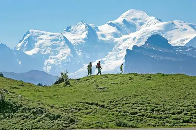 three people standing on a hill in front of a snow covered mountain at Village Vacances le Bérouze in Samoëns