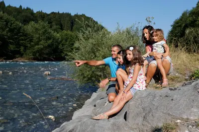 a group of people sitting on a rock by a river at Village Vacances le Bérouze in Samoëns