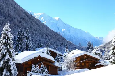 a log cabin in the snow with mountains in the background at Residence La Verte 24- Aux Pieds des pistes! in Chamonix-Mont-Blanc