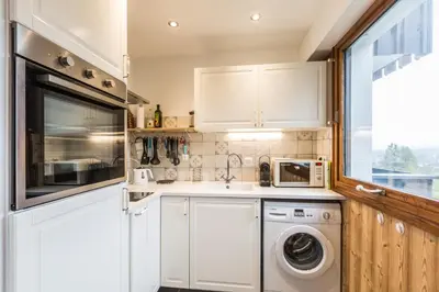 a kitchen with white cabinets and a washer and dryer at Apartment Le Pied du Brevent - Walk to Ski Lift, Chamonix Getaway in Chamonix-Mont-Blanc