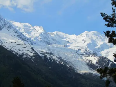 a snow covered mountain with trees in the foreground at Apartment Le Pied du Brevent - Walk to Ski Lift, Chamonix Getaway in Chamonix-Mont-Blanc