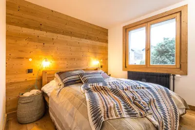 a bedroom with a bed with a wooden wall at Appartement Native in Chamonix-Mont-Blanc