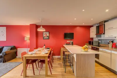 a kitchen with red walls and a table with chairs at BIOLAY 2 - Alpes Travel - Central Chamonix - Sleeps 4-6 in Chamonix-Mont-Blanc