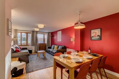 a living room with a wooden table and red walls at BIOLAY 2 - Alpes Travel - Central Chamonix - Sleeps 4-6 in Chamonix-Mont-Blanc