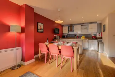 a kitchen with red walls and a table and chairs at BIOLAY 2 - Alpes Travel - Central Chamonix - Sleeps 4-6 in Chamonix-Mont-Blanc