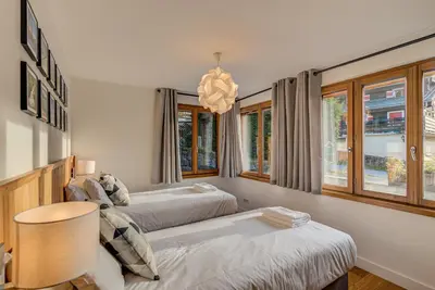 two beds in a room with windows and a chandelier at BIOLAY 2 - Alpes Travel - Central Chamonix - Sleeps 4-6 in Chamonix-Mont-Blanc
