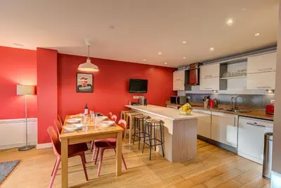 a kitchen with red walls and a table and chairs at BIOLAY 2 - Alpes Travel - Central Chamonix - Sleeps 4-6 in Chamonix-Mont-Blanc