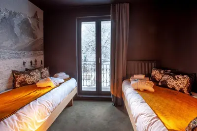 two beds in a room with a window at La Folie Douce Hotels Chamonix in Chamonix-Mont-Blanc
