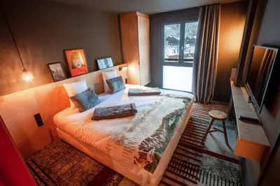 a bedroom with a bed with a television and a window at La Folie Douce Hotels Chamonix in Chamonix-Mont-Blanc
