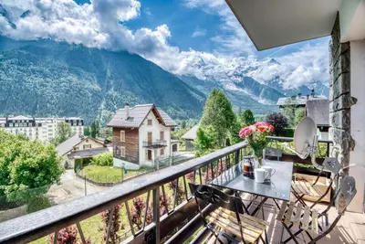 a balcony with a table and chairs and mountains at Aran Apartment - Chamonix in Chamonix-Mont-Blanc