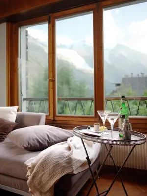 a room with a table with two glasses and a window at Aran Apartment - Chamonix in Chamonix-Mont-Blanc