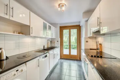 a large kitchen with white cabinets and a glass door at Aran Apartment - Chamonix in Chamonix-Mont-Blanc