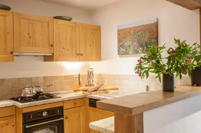 a kitchen with wooden cabinets and a painting on the wall at Petite Savoyarde - Chamonix in Chamonix-Mont-Blanc