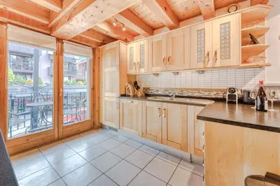 a kitchen with wooden cabinets and a large window at Morgane Apartment in Chamonix-Mont-Blanc