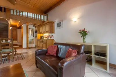 a living room with a brown leather couch and a kitchen at Polaris - Chamonix in Chamonix-Mont-Blanc
