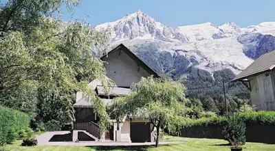 a house with a snow covered mountain in the background at Chalet des Lacs - Chamonix in Chamonix-Mont-Blanc